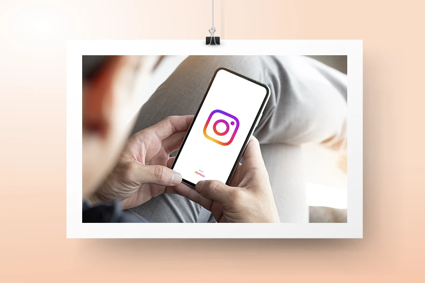 Instagram-mainonta palvelusivun kuvituskuva, jossa henkilö pitää kädessään puhelinta, jossa näkyy Instagramin logo.