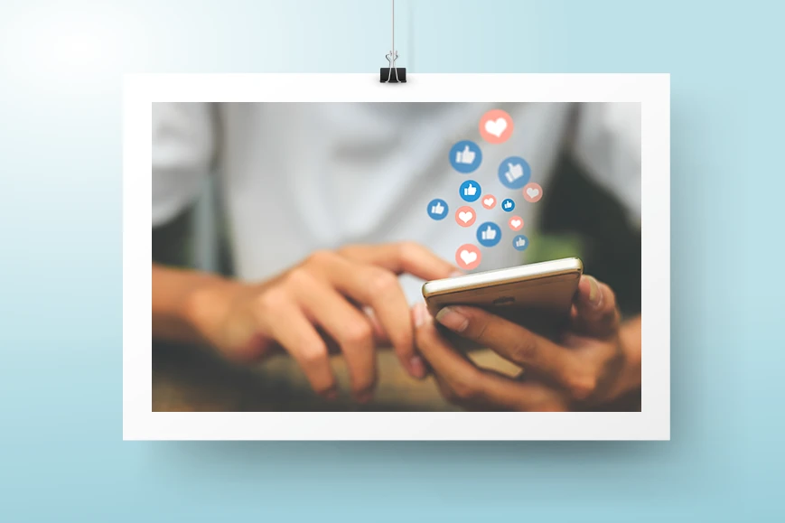 Sosiaalisen median mainonta -palvelusivun kuvituskuva, jossa henkilö pitää puhelinta kädessään. Puhelimesta leijailee sosiaalisen median tykkäysten kuvakkeita.