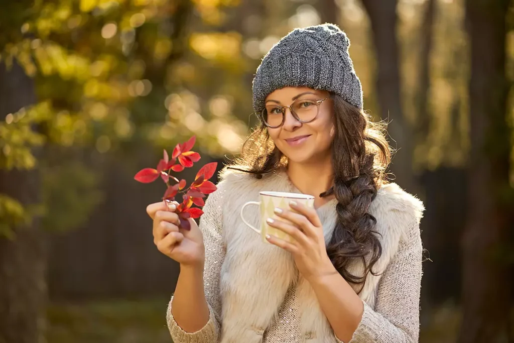 Esimerkkikuva, nainen juo kahvia ulkona syksyllä